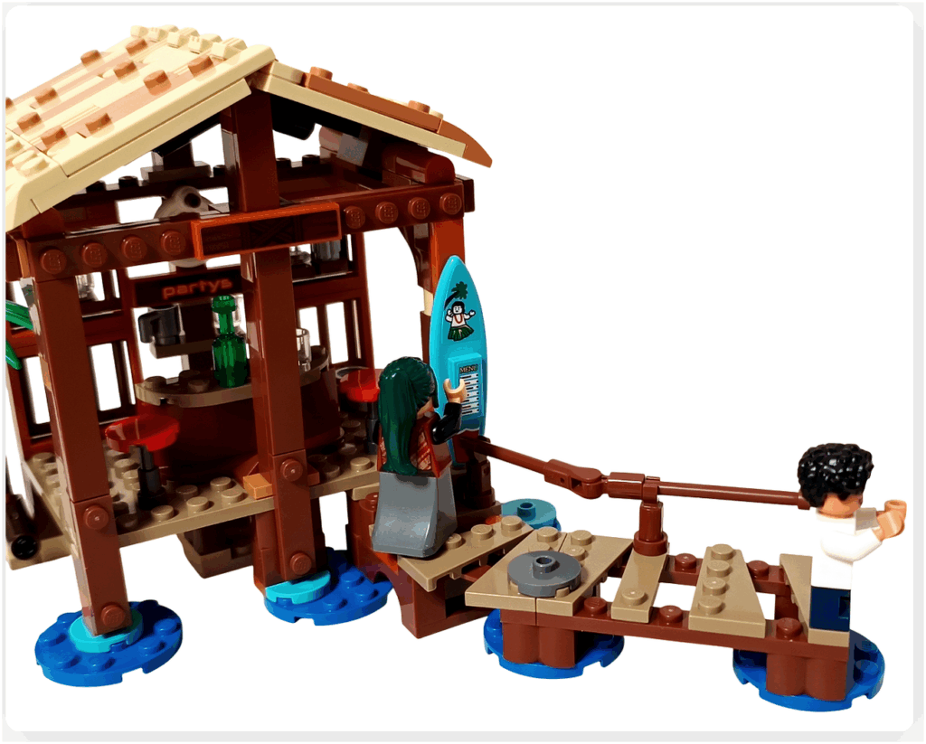 レゴ ONE PIECE 75636「フーシャ村」の情景。桟橋へ向かうルフィと、サーフボード型メニューの横で掃除するマキノが配置され、南国風の軽やかな村の日常が表現されたシーン。