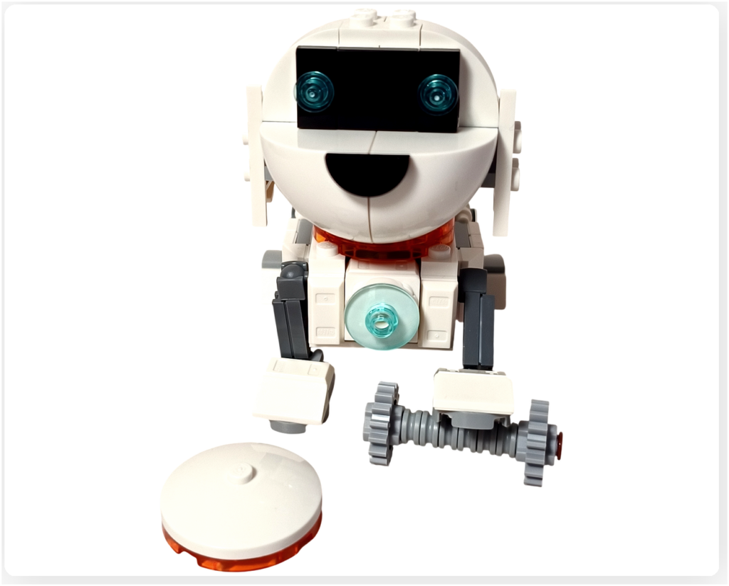 レゴ 31164 うちゅうロボット 「うちゅう犬」がごほうびのパーツを前に喜んでいる様子。白いロボット犬が正面を向き、目を輝かせながら小さなパーツを見つめているシーン。